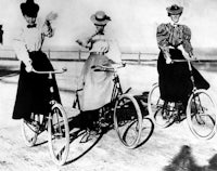 three women riding bicycles on a beach